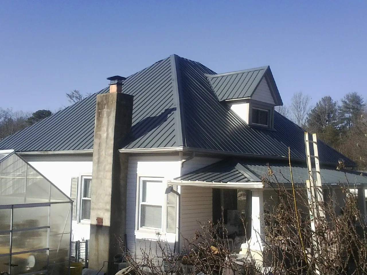 Dark blue standing seam metal roof on a white farmhouse with dormer — Slate & Tile Roof Repair by Roofing Brothers in New Concord