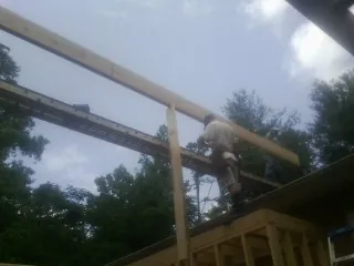 Carpenter setting a ridge beam over a new addition frame — Ice Dam Removal by Roofing Brothers in New Concord