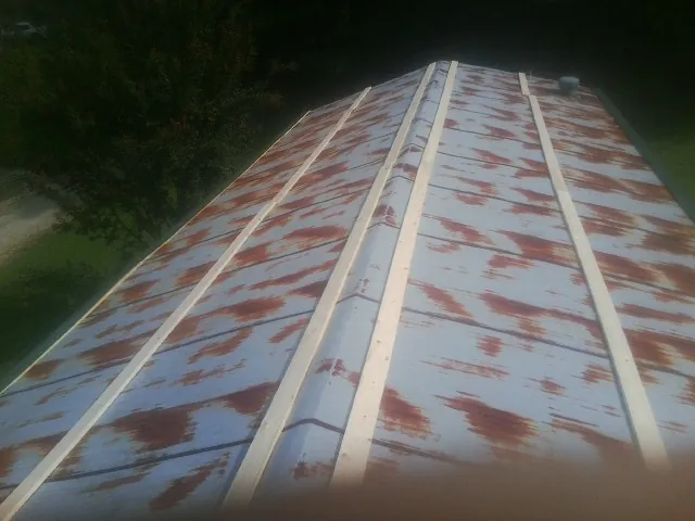 Rusted metal roof panels with new wood purlins before replacement — Storm Damage Roof Repair in New Concord by Roofing Brothers