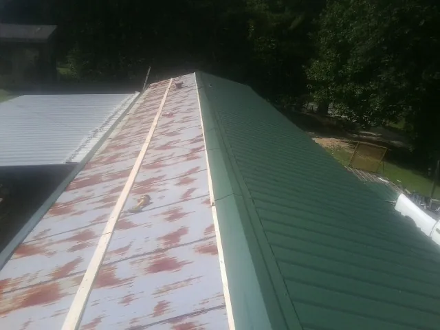 Old rusted panels beside newly installed green metal roofing — Wind Damage Roof Repair by Roofing Brothers in New Concord