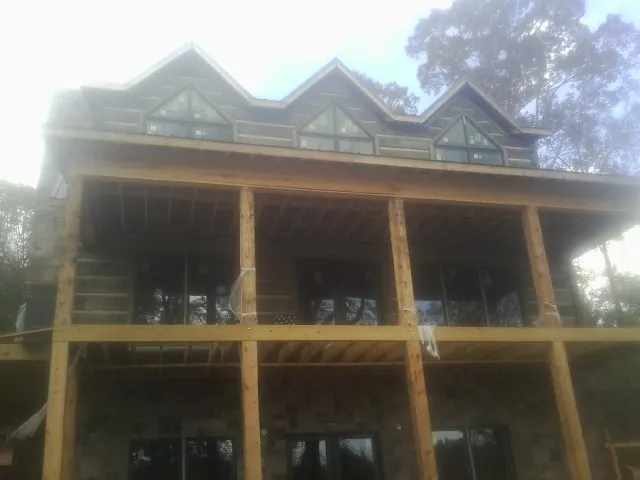 Dormers and porch framing on a large log home under construction — Roof Coating work by our crew in New Concord