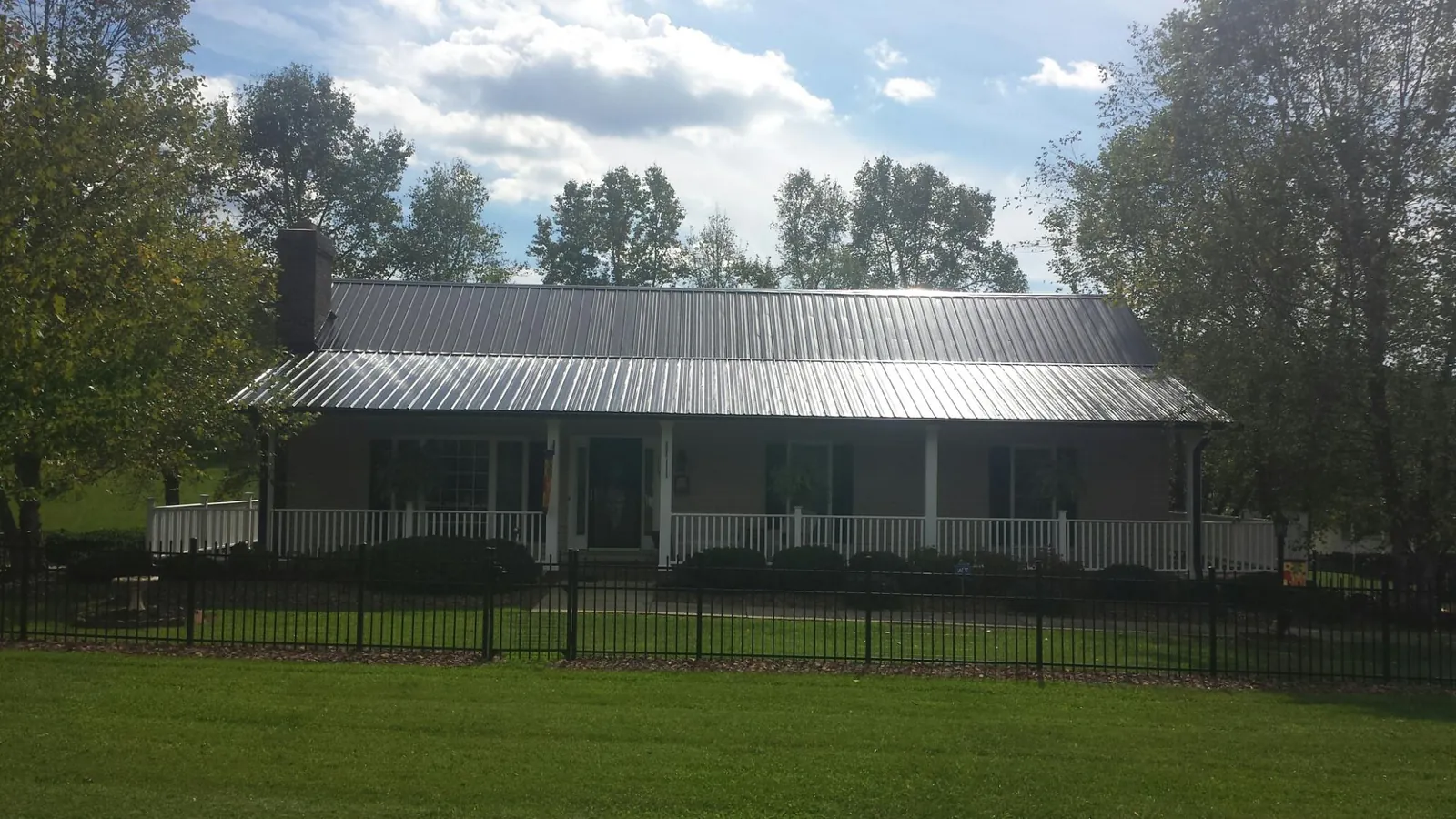 Gray metal roof on a brick ranch with a full width front porch — Gutter Guard Installation work by our crew in New Concord