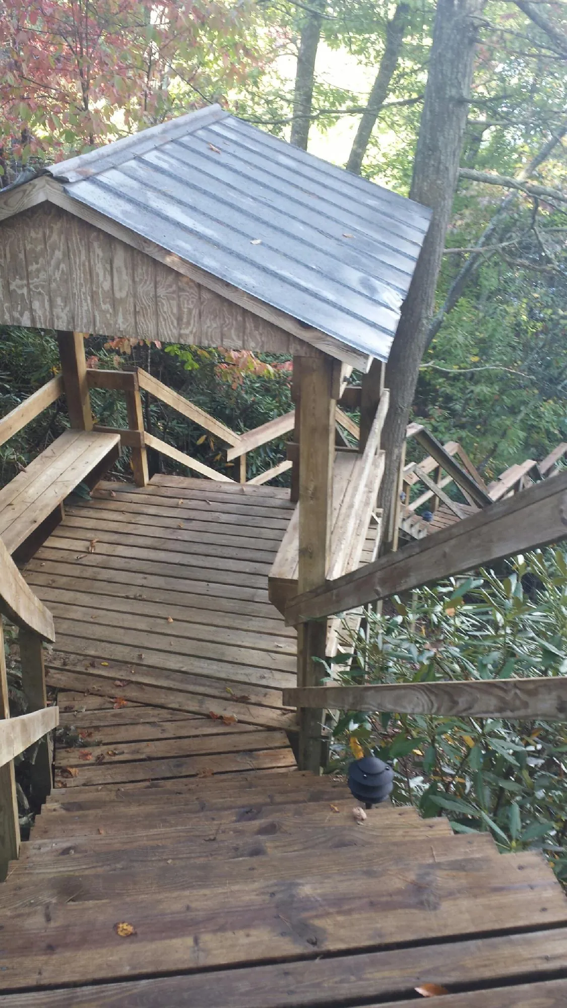 Metal roofed shelter over wooden steps on a wooded walkway — Skylight Repair & Installation work by our crew in New Concord