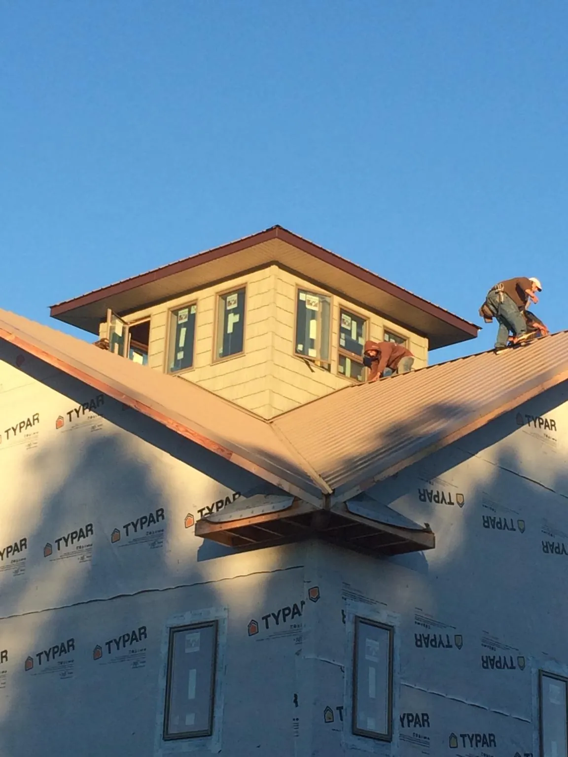 Roofers working around a rooftop cupola on a new metal roof at sunset — Roof Waterproofing in New Concord by Roofing Brothers
